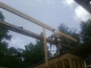 Carpenter setting a ridge beam over a new addition frame — Ice Dam Removal by Roofing Brothers in Hankinson