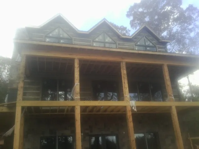 Dormers and porch framing on a large log home under construction — Roof Coating work by our crew in Hankinson