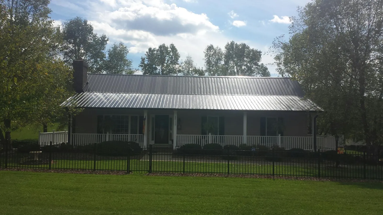 Gray metal roof on a brick ranch with a full width front porch — Gutter Guard Installation work by our crew in Hankinson