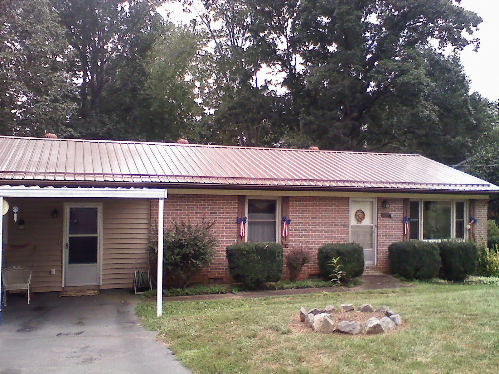 Bronze metal roof and carport on a brick ranch home — Roof Repair work by our crew in Hankinson