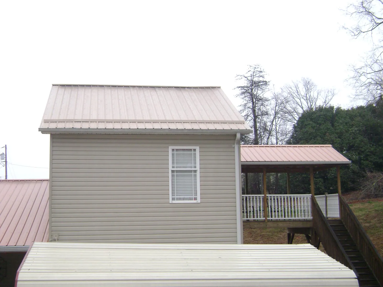Tan metal roofs on a two story addition and attached porch, from a Roof Replacement job in Hankinson