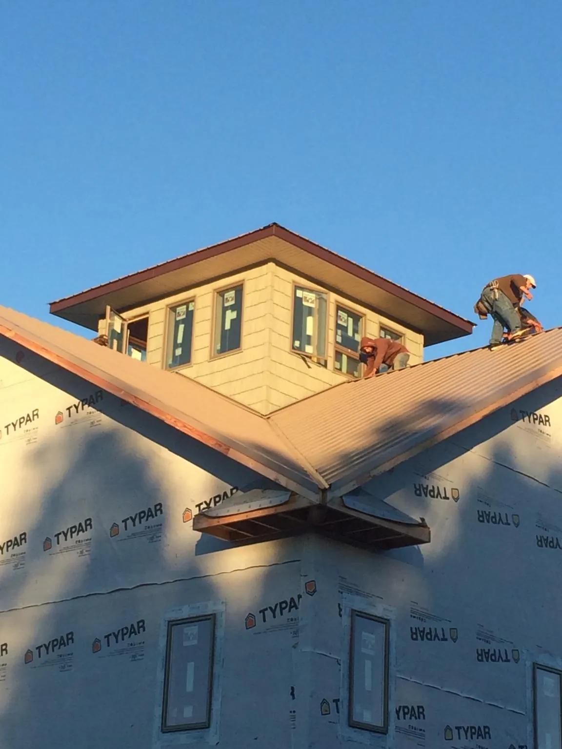 Roofers working around a rooftop cupola on a new metal roof at sunset — Roof Waterproofing in Hankinson by Roofing Brothers